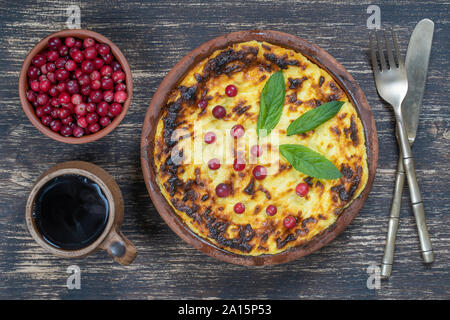 Süße Quark Auflauf mit Rosinen und Grieß auf hölzernen Tisch. Keramische Schüssel mit gebackenen Cottage Käse Auflauf, Nahaufnahme, Ansicht von oben Stockfoto