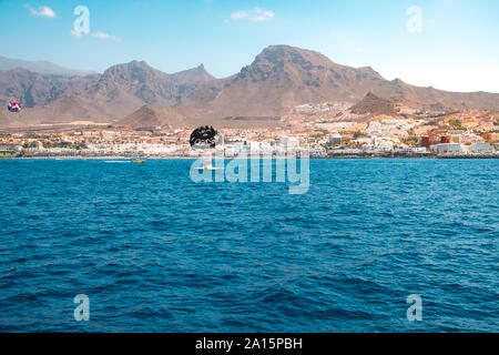 Teneriffa, Spanien - August 2019: Meerblick an der Küste von Teneriffa (Coasta Adeje) mit Motorboot und Parasail Stockfoto