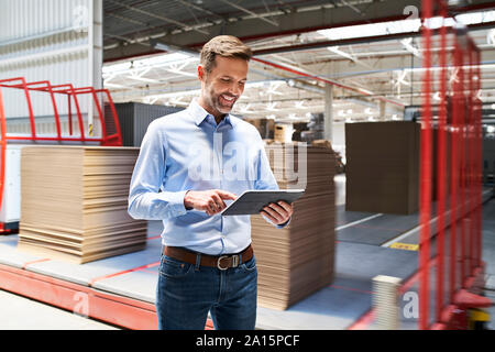 Lächelnd Geschäftsmann mit Tablette in einer Fabrik Stockfoto