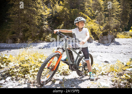 Junge in den Bergen mit seinem e-Mountainbike Stockfoto