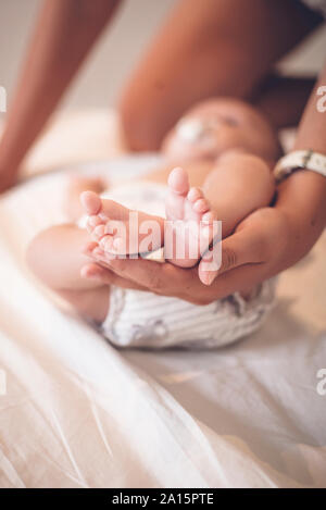 Die Mutter von Hand mit winzigen Füßen von baby boy, close-up Stockfoto