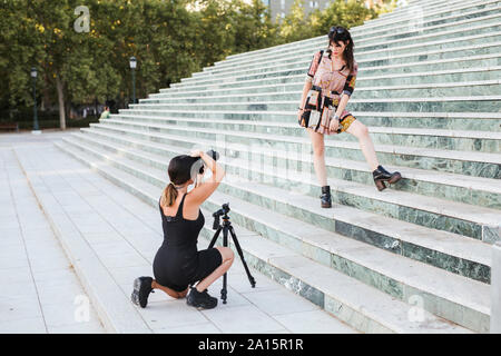 Junge Frau mit gemusterten Kleid für ein Fotoshooting auf der Treppe posiert Stockfoto