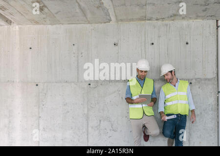 Zwei Arbeiter mit Tablet-PC auf der Baustelle Stockfoto