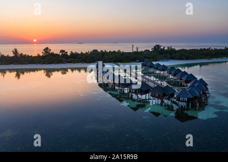 Malediven, Insel Olhuveli, Resort Bungalows auf Süd Male Atoll Lagune bei Sonnenuntergang Stockfoto