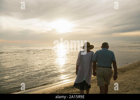 Rückansicht des Senior paar Hand in Hand am Strand bei Sonnenuntergang, Liepaja, Lettland Stockfoto