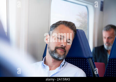 Reifer Mann im Zug sitzen, schlafen Stockfoto