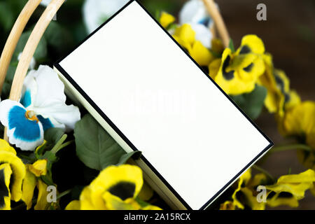 In der Nähe von Leer weißes Kästchen in Korb mit Blumen auf Holztisch. Rustikale Dekoration und Geschenke Stockfoto