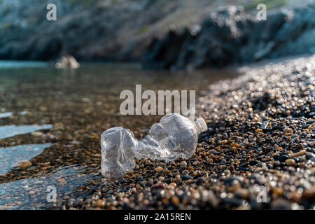 Leere Plastikflasche liegen auf steinigem Strand am Meer Stockfoto