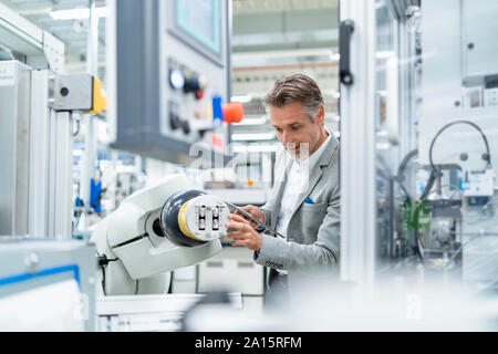 Geschäftsmann mit Tablette montageroboter in einer Fabrik Stockfoto