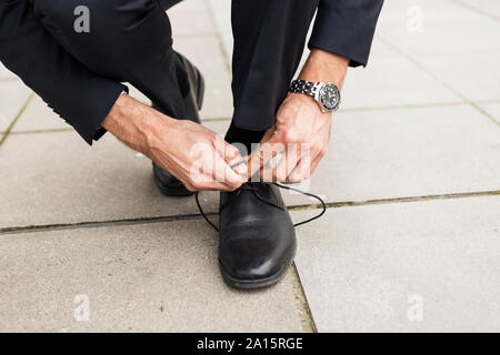 Geschäftsmann seinen Schuh auf Pflaster binden, close-up Stockfoto