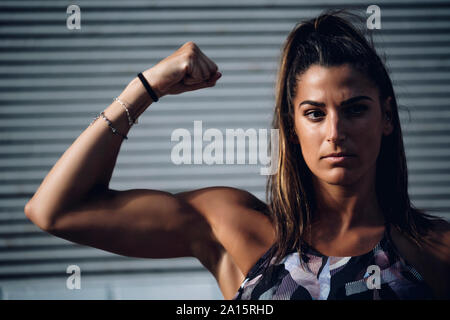 Portrait von selbstbewussten jungen Frau flexing Muskeln Stockfoto