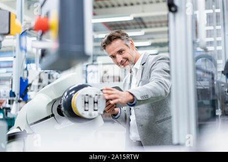 Geschäftsmann mit Tablette montageroboter in einer Fabrik Stockfoto