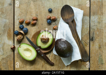 Halbierte Avocado, Heidelbeeren und die Muttern an den hölzernen Tisch von oben gesehen Stockfoto