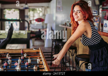 Portrait von glücklichen jungen Frau spielen Tischfußball in einer Sports Bar Stockfoto