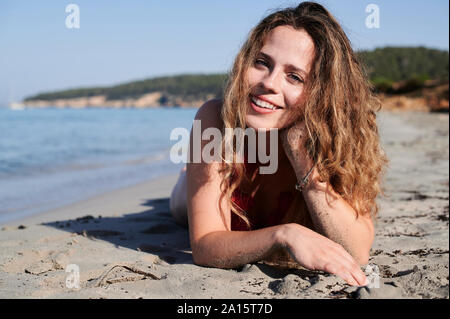 Porträt der glückliche junge Frau am Strand liegen Stockfoto