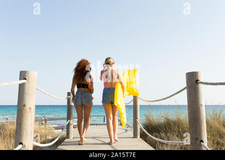 Ansicht der Rückseite des jungen Frauen mit gelb Luftmatratze und Sonnenschirm zu Fuß zum Strand Stockfoto