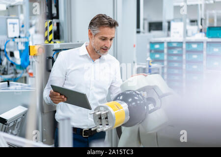 Geschäftsmann mit Tablette montageroboter in einer Fabrik Stockfoto