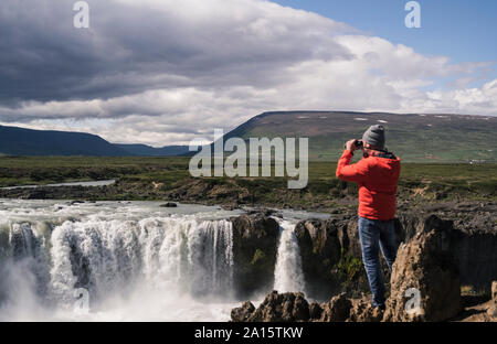 Mann am Godafoss Wasserfälle suchen, Island, mit dem Fernglas Stockfoto