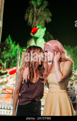 Porträt von zwei glückliche junge Frauen, die auf einem Jahrmarkt bei Nacht Stockfoto
