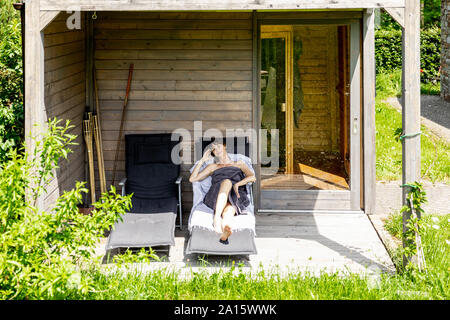 Frau Entspannung auf eine Lounge außerhalb der Sauna Stockfoto