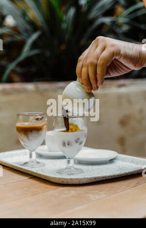 Hand gießen Espresso in ein Glas Stockfoto