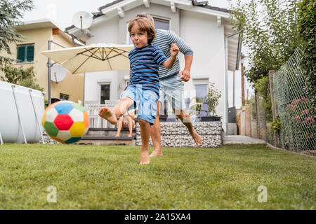 Vater und Sohn im Garten Fußball spielen Stockfoto