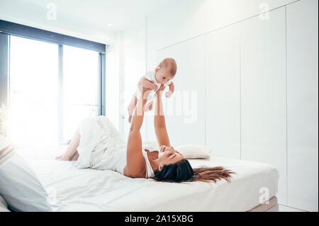Mutter spielt mit Baby im Schlafzimmer Stockfoto