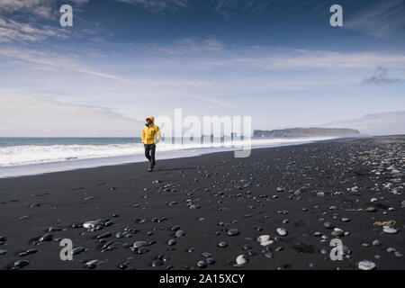 Reifer Mann zu Fuß auf einer Lava Strand in Island Stockfoto