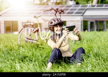 Gerne Frau sitzt auf einer Wiese mit Fahrrad eine selfie Stockfoto