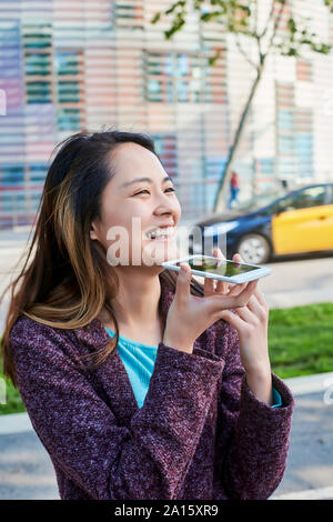 Glückliche Frau Senden einer Sprachnachricht mit Handy, Barcelona, Spanien Stockfoto