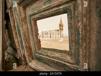 Blick durch ein Fenster der Kirche in das verlassene Dorf Ilha dos Tigres, Angola. Stockfoto