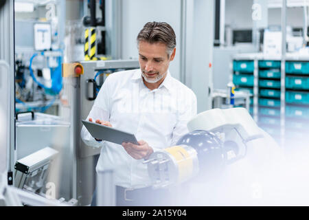 Geschäftsmann mit Tablette montageroboter in einer Fabrik Stockfoto