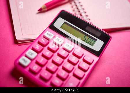 Nahaufnahme von Rechner und Notebook mit Bleistift auf pink Schreibtisch Stockfoto