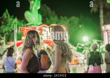 Zwei junge Frauen auf einem Jahrmarkt bei Nacht Stockfoto