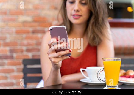 Die Hand der jungen Frau an Street Cafe holding Smartphone, close-up Stockfoto