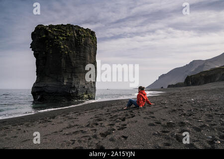Frau auf Lava Beach im Südosten von Island, mit Blick auf das Meer Stockfoto