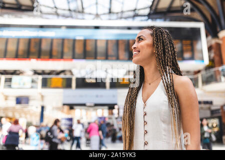 Glückliche junge Frau am Bahnhof, London, UK Stockfoto