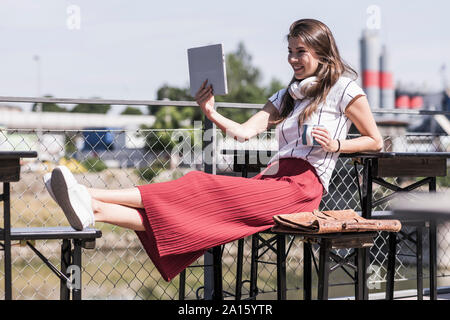 Junge Frau Entspannung in einem Biergarten mit Tablet Stockfoto