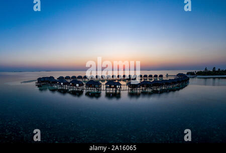 Malediven, Insel Olhuveli, Resort Bungalows auf Süd Male Atoll Lagune bei Sonnenuntergang Stockfoto