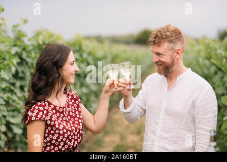 Paar Toasten mit weißen Wein in den Weinbergen Stockfoto