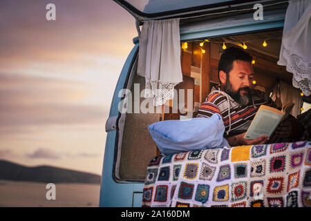 Reifer Mann lag in Van und ein Buch lesen Stockfoto