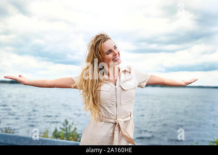 Glückliche Frau an der Lakeside mit ausgestreckten Armen Stockfoto