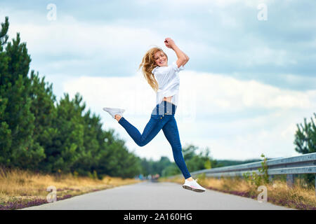 Fröhliche Frau springen auf ländlichen Straßen Stockfoto