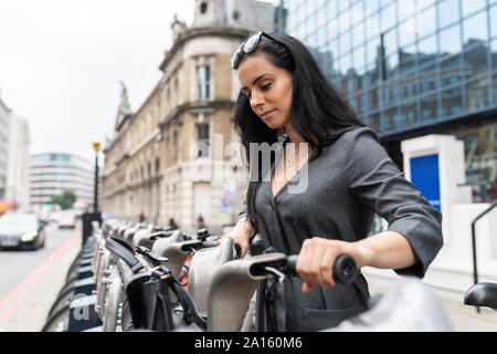 Frau in der Stadt über einen Fahrradverleih, Pendeln, London, UK Stockfoto