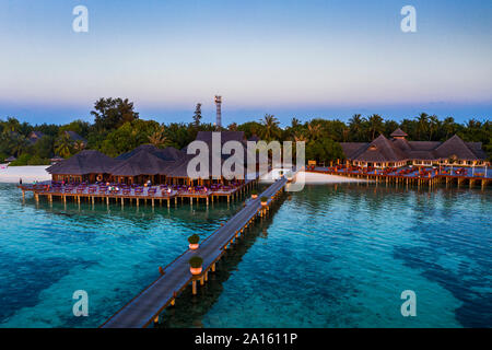 Malediven Olhuveli Island, Pier und Resort Süd Male Atoll Lagune bei Sonnenuntergang Stockfoto