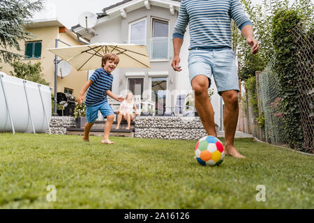 Vater und Sohn im Garten Fußball spielen Stockfoto