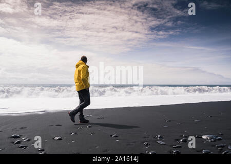 Reifer Mann zu Fuß auf einer Lava Strand in Island Stockfoto