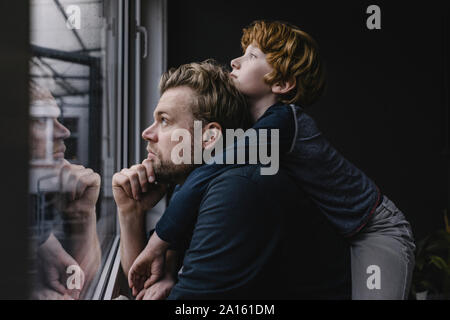 Vater und Sohn Blick aus Fenster auf Regentag Stockfoto