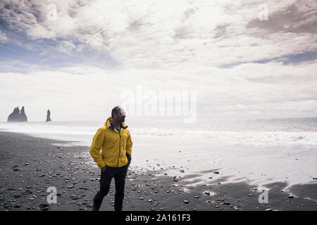 Reifer Mann zu Fuß auf einer Lava Strand in Island Stockfoto