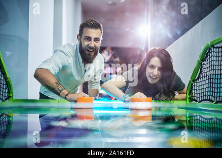 Glückliches Paar Air Hockey spielen und Spaß in der Spielhalle Stockfoto